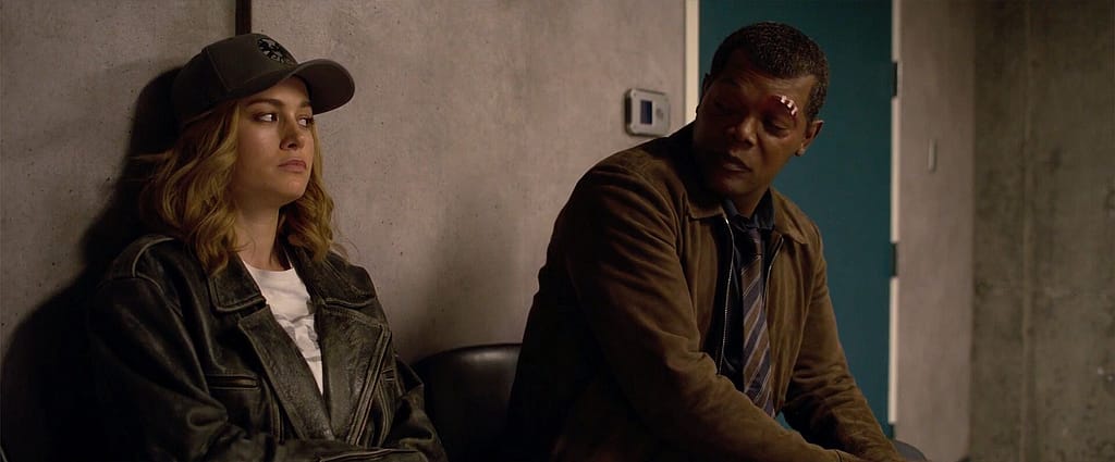 A woman (Captain Marvel) and a man (Nick Fury) sit and have a discussion