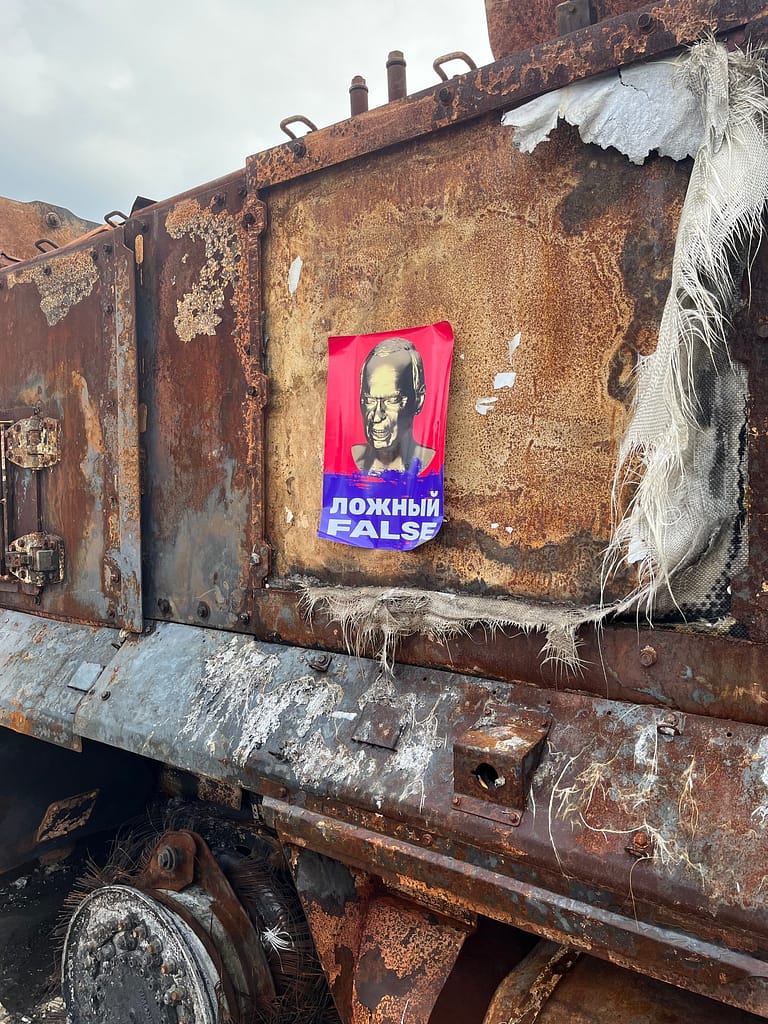 Protest poster affixed to a burned Russian tank